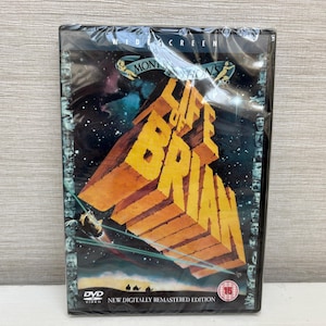 Könnte beinhalten: DVD des Films "Das Leben des Brian" in Plastikfolie. Das Cover zeigt den Titel in großen, orangefarbenen 3D-Buchstaben vor einem Sternenhintergrund. Es ist eine digital überarbeitete Ausgabe.
