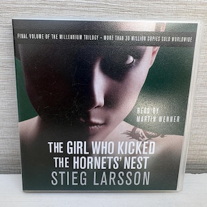 May include: Audiobook cover for "The Girl Who Kicked the Hornets' Nest" by Stieg Larsson. The cover features a close-up of a person's face with dark shadows and the text "Final Volume of the Millennium Trilogy".