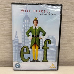 May include: DVD of the movie "Elf" starring Will Ferrell and James Caan. The cover features Ferrell in an elf costume in front of a cityscape. The word "elf" is prominently displayed in large green letters.