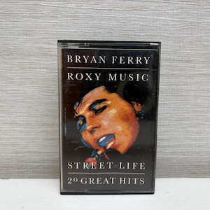 May include: A vintage cassette tape for the album "Street Life" by Bryan Ferry and Roxy Music. The cover features a portrait of a person with a blue and orange color scheme. The text reads "20 Great Hits".
