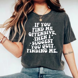 Op de afbeelding: Donkergrijs t-shirt met de witte tekst "IF YOU FIND ME OFFENSIVE, THEN I SUGGEST YOU QUIT FINDING ME". Het shirt heeft een relaxte pasvorm en korte mouwen. De tekst is vetgedrukt en sans-serif.