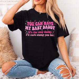 May include: Black t-shirt with the text "YOU CAN HAVE MY BABY DADDY It's the step daddy I'll curb stomp you for." in pink and white lettering. The shirt is a crew neck style.