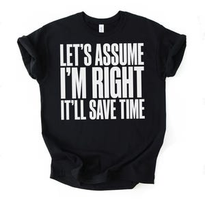 Puede incluir: Camiseta negra de cuello redondo con el texto blanco "LET'S ASSUME I'M RIGHT IT'LL SAVE TIME" impreso en la parte delantera. La camiseta está doblada, con las mangas enrolladas. El fondo es blanco liso.