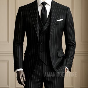 Può includere: Un abito nero gessato con camicia bianca, cravatta nera e gilet. L'abito è esposto su un manichino. È visibile un fazzoletto da taschino bianco. Il testo "AMANIQUE ATTIRE" è stampato in basso a destra.
