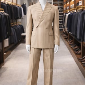 May include: A tan double-breasted suit with vertical pinstripes is displayed on a mannequin. The suit includes a jacket with two rows of buttons and matching trousers. The mannequin is in a clothing store with racks of suits in the background.