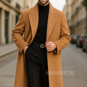May include: A camel-colored overcoat with a classic design, worn over a black turtleneck and black trousers. The coat features a notched lapel and a single-breasted closure. A black belt with a gold buckle is visible. The text "AMANIQUEATTIRE" is at the bottom.