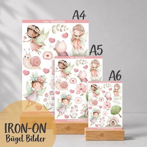 Könnte beinhalten: Drei rechteckige Bögen mit der Beschriftung A4, A5 und A6, die Bügelbilder mit Illustrationen von Feen, Schnecken, Schmetterlingen, Blumen und Herzen in Rosa-, Grün- und Brauntönen zeigen. Der Text Iron-Bügelbilder ist sichtbar.