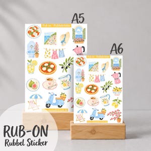 Könnte beinhalten: Zwei Bögen mit Rubbelstickern, beschriftet mit A5 und A6, mit Aquarellillustrationen italienischer Motive wie Pizza, einem blauen Roller, einer Kaffeekanne, Zitronen, Feigen, einem Sonnenschirm, einem Brunnen und einer Küstenlandschaft.