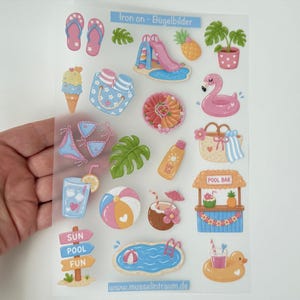 Könnte beinhalten: Ein transparenter Bogen mit Bügelbildern, der bunte sommerliche Illustrationen zeigt, darunter Flip-Flops, eine Poolrutsche, eine Ananas, einen Flamingo-Schwimmring, eine Strandtasche, eine Poolbar, einen Kokosnuss-Drink und Schilder mit Sun Pool Fun.