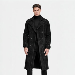 May include: A long, black suede coat with a double-breasted design. The coat features a notched collar, button closures, and a tailored fit. The sleeves have buttoned cuffs. The coat is worn over a black turtleneck and black pants.