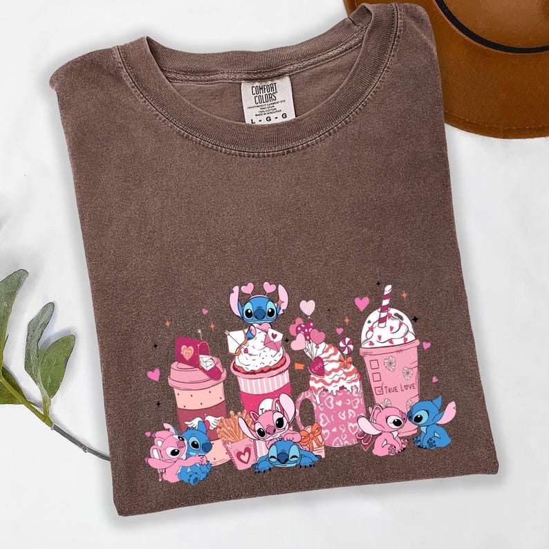 May include: Brown t-shirt with a crew neck and a graphic featuring cartoon characters and pink beverages. The graphic includes the text "True Love" and various heart shapes. The shirt is labeled "Comfort Colors".