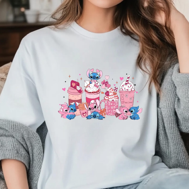 May include: White t-shirt featuring a colorful graphic of cartoon characters and pink desserts. The design includes pink and blue characters with hearts, and various treats like milkshakes and sundaes. The words "True Love" are visible on one of the cups.