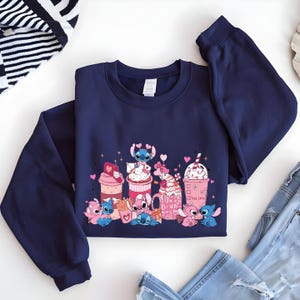 May include: Navy blue sweatshirt featuring a colorful graphic of cartoon characters with various pink and white desserts. The design includes hearts and the words "True Love" on a pink cup. The sweatshirt is made of a soft material.
