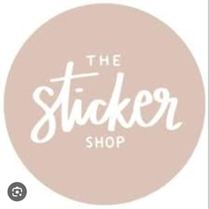 May include: A circular logo with a light dusty pink background featuring the white text THE sticker SHOP centered in the middle. The word sticker is written in a white cursive script font, while THE and SHOP are in block letters.