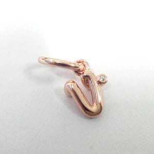 Puede incluir: Charm de letra "V" en oro rosa con un pequeño acento de diamante. El charm está unido a un pequeño lazo para facilitar su fijación a un collar o pulsera. Una delicada pieza de joyería.