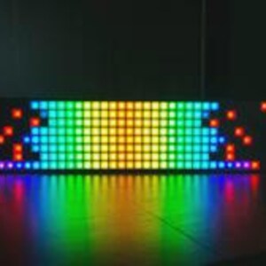 Op de afbeelding: Een rechthoekig LED-lichtpaneel met een raster van verlichte vierkante pixels. Het display toont een levendig kleurenspectrum, verlopend van rood en oranje aan de buitenranden naar geel, groen en blauw in het midden, inclusief een reflectie.