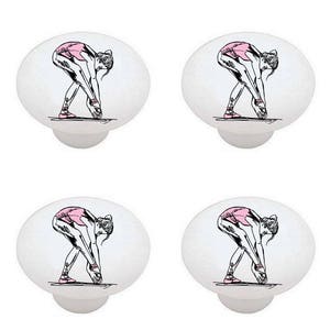 May include: Set of four ceramic cabinet knobs featuring a black and white line drawing of a ballerina in a pink leotard stretching. The knobs are white with a glossy finish.