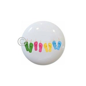 May include: A white ceramic ornament with a string of colorful flip-flops hanging from clothespins.