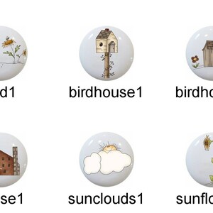 May include: Set of 10 ceramic knobs with various designs, including an angel, bird, birdhouse, church, flower, house, sun and clouds, sunflower, and tree. The knobs are white with blue accents and feature hand-painted details.