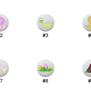 May include: Ten ceramic knobs with dinosaur and jungle-themed designs. The knobs are white with colorful cartoon images of dinosaurs, palm trees, bones, and a volcano.
