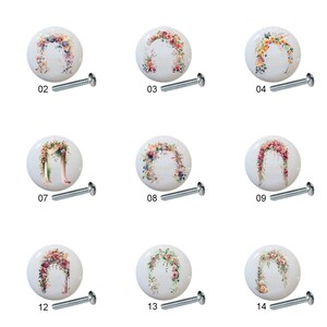 May include: Set of 14 floral wedding arch ceramic cabinet knobs with silver screws. The knobs feature various floral arrangements and arches in shades of pink, white, and green.