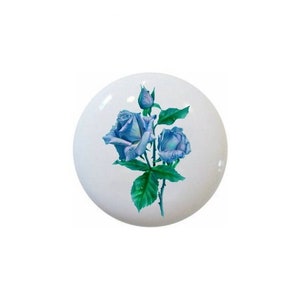 May include: A white, round decorative knob featuring a detailed illustration of blue roses with green leaves and a bud. The floral design is centered on the knob, creating a classic and elegant aesthetic.