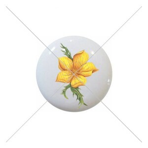 May include: A white ceramic knob with a yellow flower design. The flower has five petals and a green stem with leaves.