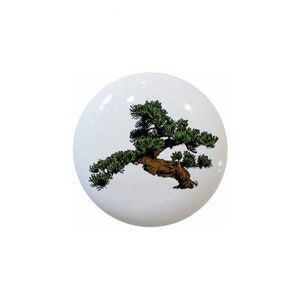 May include: A white ceramic knob with a green and brown bonsai tree design.