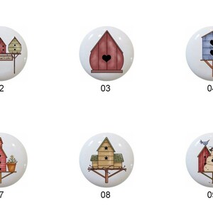 May include: Ten different ceramic knobs with birdhouse designs. Each knob features a different birdhouse design with various colors and patterns. The knobs are round and white with a black outline.