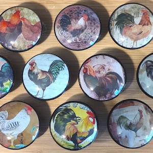 May include: Set of ten round, glass cabinet knobs with a black metal base. Each knob features a different vintage illustration of a rooster or hen.