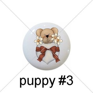 May include: Five round, white ceramic ornaments with different designs.  The first four ornaments feature a cartoon puppy in a pocket with different designs. The fifth ornament has the words "Puppy Love" with a bone graphic.