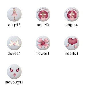 May include: A collection of decorative cabinet knobs with various designs. The knobs feature images of angels, doves, butterflies, flowers, hearts, and ladybugs. Some knobs have text that reads "DO MY VOLONTIN". The knobs are white with colorful illustrations.