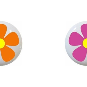 May include: Four round ceramic buttons with a flower design. The flowers are in shades of green, orange, pink, and teal with a yellow center.