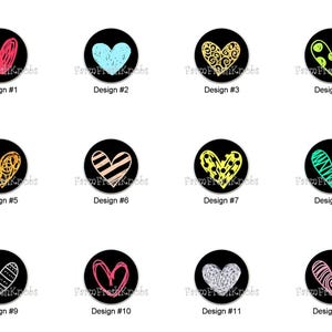 May include: A collection of twelve black cabinet knobs, each featuring a unique heart design in various colors and styles. Designs include red, blue, gold, and green hearts with different patterns. Each knob is labeled with a design number.