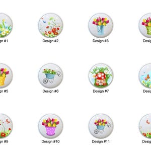 May include: A collection of twelve decorative cabinet knobs with various floral and nature-themed designs. Each knob features a different illustration, including tulips, butterflies, and a mushroom house. The designs are labeled with numbers.