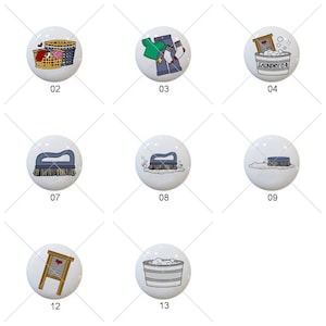 May include: A set of 13 ceramic knobs featuring laundry-themed illustrations. The knobs are white with black outlines and feature images of laundry baskets, clothes, brushes, and other laundry-related items.