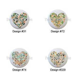 May include: Four white cabinet knobs with heart-shaped leaf designs. Each knob features a different arrangement of green, orange, and brown leaves. The designs are labeled with numbers: #31, #72, #74, and #329.