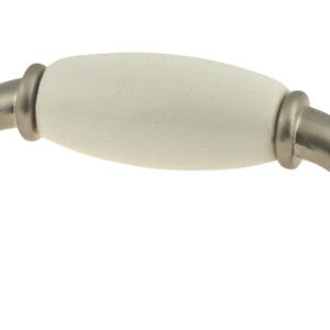 May include: White ceramic cabinet knob with a nickel finish. The knob has a curved shape and a smooth, rounded surface.