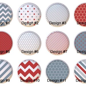 May include: Twelve round decorative buttons with various patterns and designs. The designs include chevrons, polka dots, stripes, and geometric shapes in red, white, and blue. Each button is labeled with a design number.