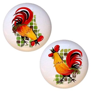 May include: Two ceramic knobs with a rooster design. The rooster is yellow with red and black accents. The background is a green and white checkered pattern.