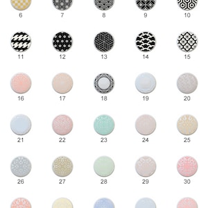 May include: Thirty-nine round, decorative, ceramic tiles with various geometric and floral patterns. The tiles are arranged in six rows of seven tiles each. The tiles are in various colors, including gold, black, white, pink, blue, and green.