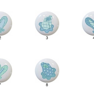 May include: Eight ceramic knobs with different blue and green patterns. The patterns include hearts, frogs, and geometric designs.