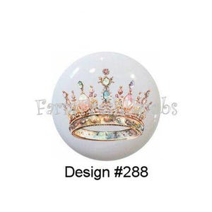 May include: Three white, round cabinet knobs with crown designs. Design #99 features a pink and silver crown. Design #288 has a gold crown. Design #332 displays a colorful crown. The text "Farmhouse Fabs" is partially visible.
