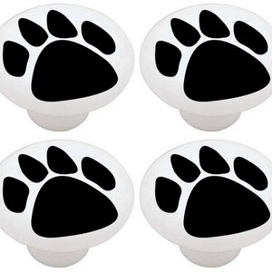 May include: Set of four white ceramic cabinet knobs with black paw print designs.