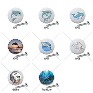 May include: Assortment of 12 ceramic cabinet knobs featuring various dolphin designs. The knobs are white with blue and gray accents. Some designs include a cartoon dolphin, a dolphin jumping out of the water, and a dolphin swimming in the ocean. The knobs are labeled with numbers and names, such as "Cartoon", "#001", "#002", "#003", "#004", "#005", "#006", "#007", "#008", "#602752", "Dreaming", "Globe", and "Treasure".