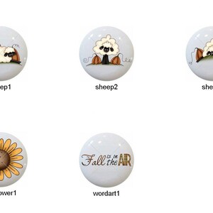 May include: Set of 8 ceramic drawer knobs with fall-themed designs.  The designs include leaves, sheep, sunflowers, and a word art design that says "Fall is in the air".