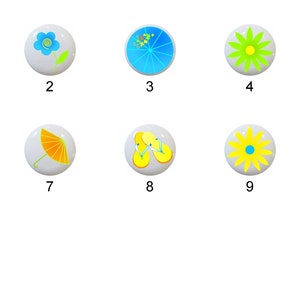 May include: Eleven white ceramic knobs with different colorful designs, including butterflies, flowers, and umbrellas. The knobs are numbered 1 through 11.