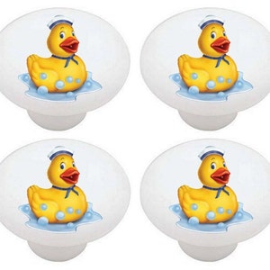 May include: Set of four white ceramic knobs with a yellow rubber ducky wearing a blue and white sailor hat and floating in blue water with white bubbles.