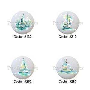May include: Four white cabinet knobs with watercolor sailboat designs. Each knob features a different sailboat illustration in shades of blue, green, and yellow. The text "Design #" followed by a number is below each knob.