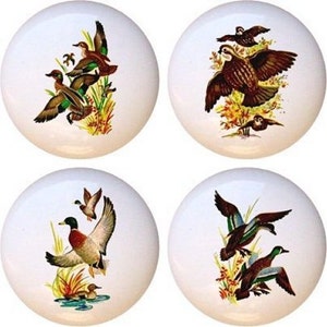 May include: Set of four ceramic cabinet knobs featuring a variety of birds, including ducks and quail, in a nature-inspired design. The knobs are white with a glossy finish.